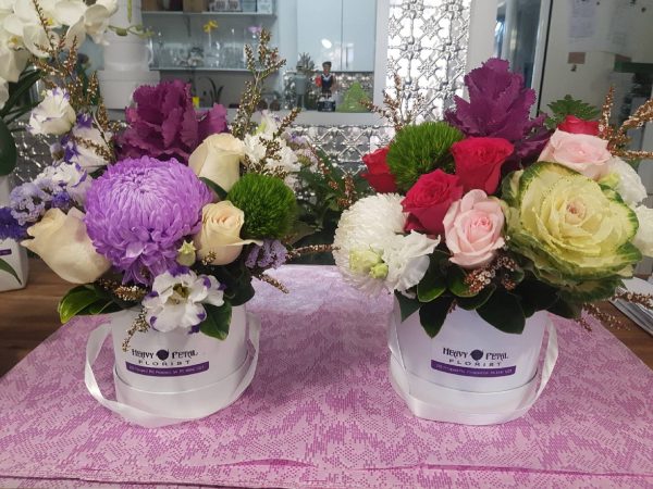 Two arrangements of flowers in hat boxes
