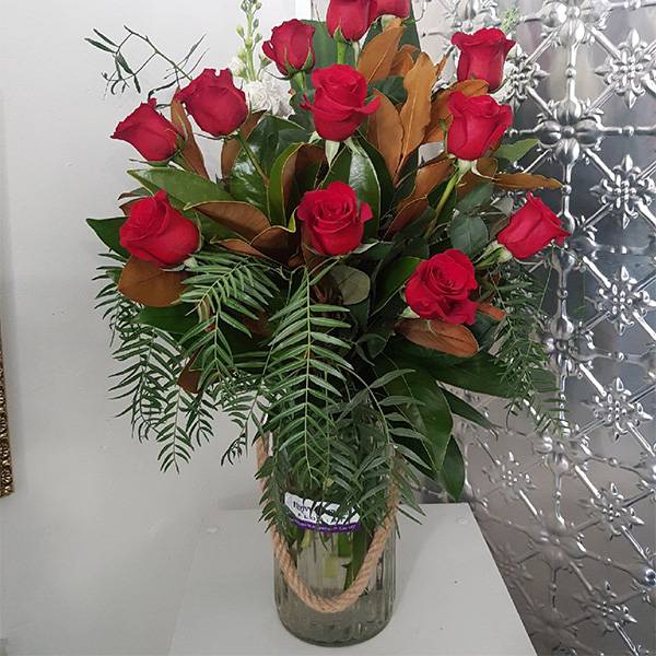 A dozen red roses in a large rustic vase