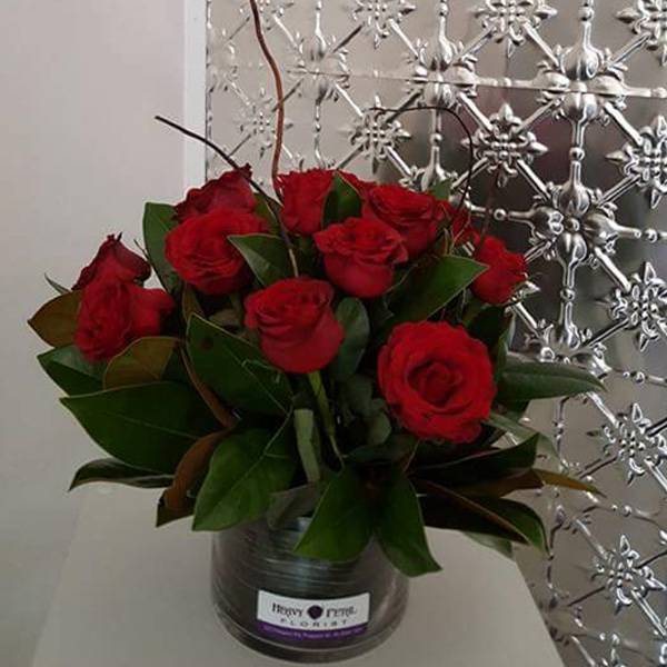 A dozen short stemmed roses in a vase