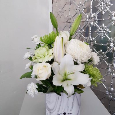 An arrangement of white flowers in a ceramic marble look vessel
