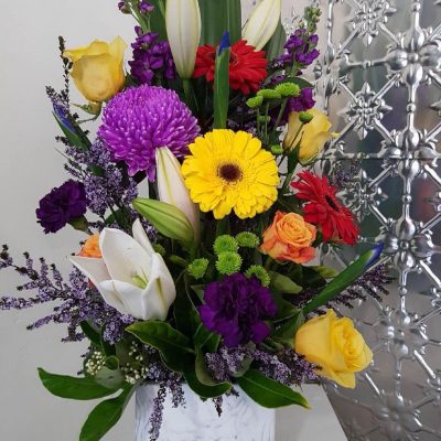 A tall arrangement of flowers in a ceramic marble look vessel.