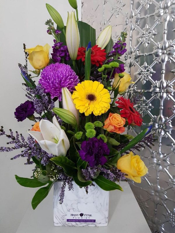 A tall arrangement of flowers in a ceramic marble look vessel.