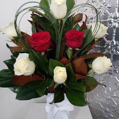 A mix of red and white roses in a tall white vase