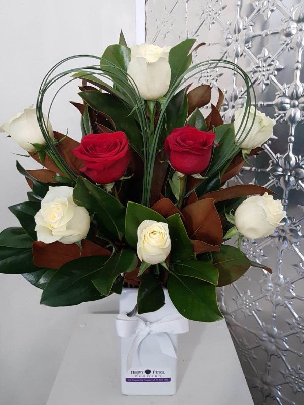 A mix of red and white roses in a tall white vase