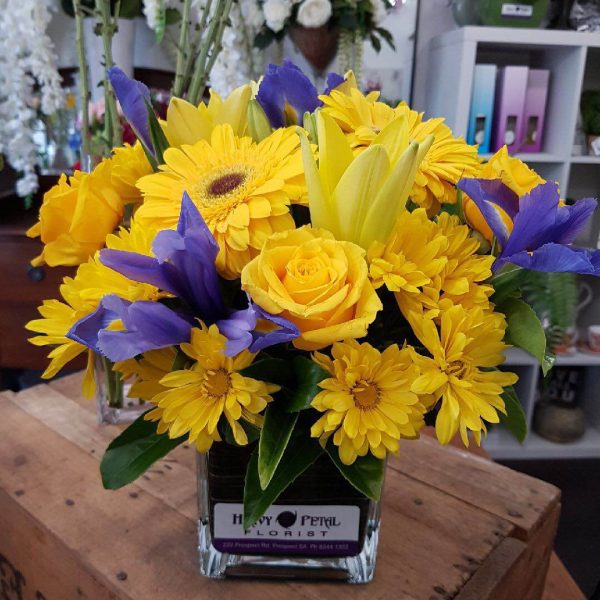 A yellow arrangement of flowers in a glass vase