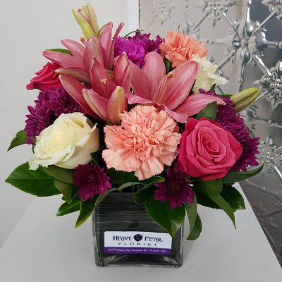 A short stemmed arrangement of flowers in a short vase