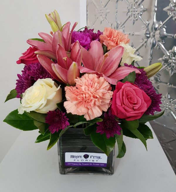 A short stemmed arrangement of flowers in a short vase