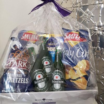 A hamper with beers, nuts, pretzels and chips.