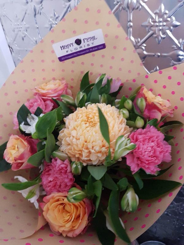 A bouquet of pink and orange flowers wrapped in paper