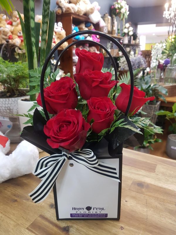 A half dozen red roses in a bag