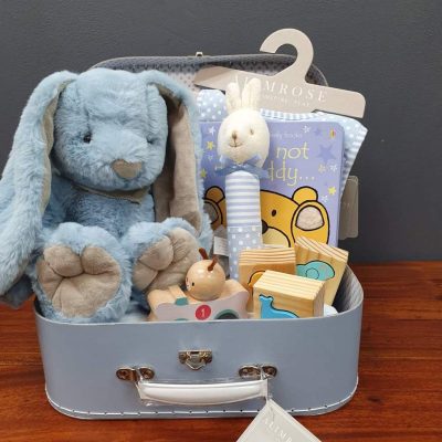 a blue suitcase hamper with various toys for a baby.