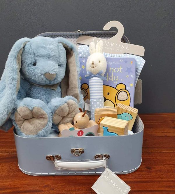 a blue suitcase hamper with various toys for a baby.
